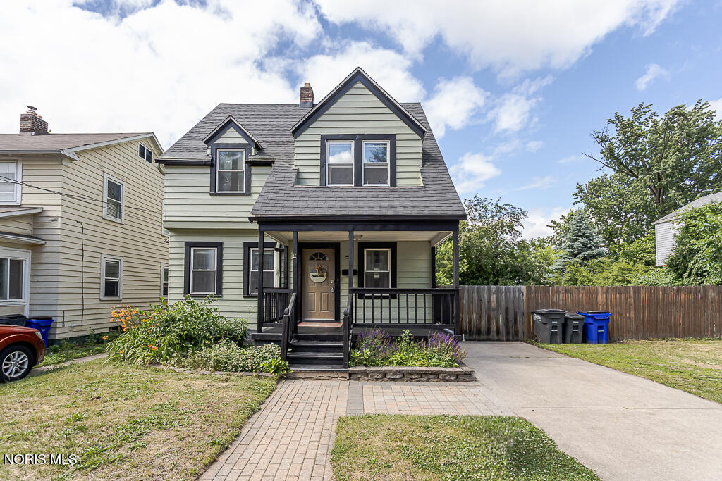 Green two-story house with a covered front porch and brick walkway.