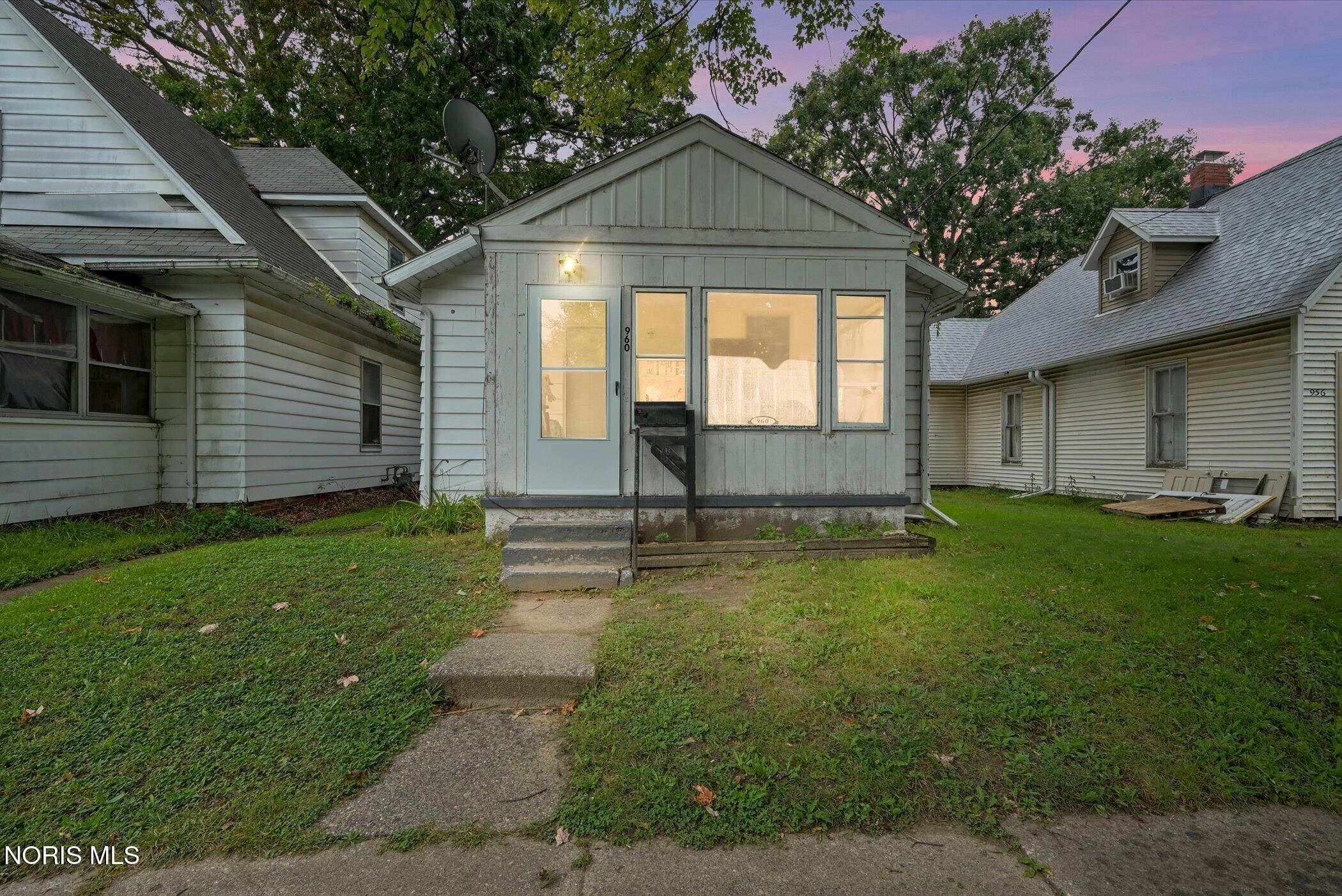 Gray single-story house with a black mailbox and concrete front steps at dusk.