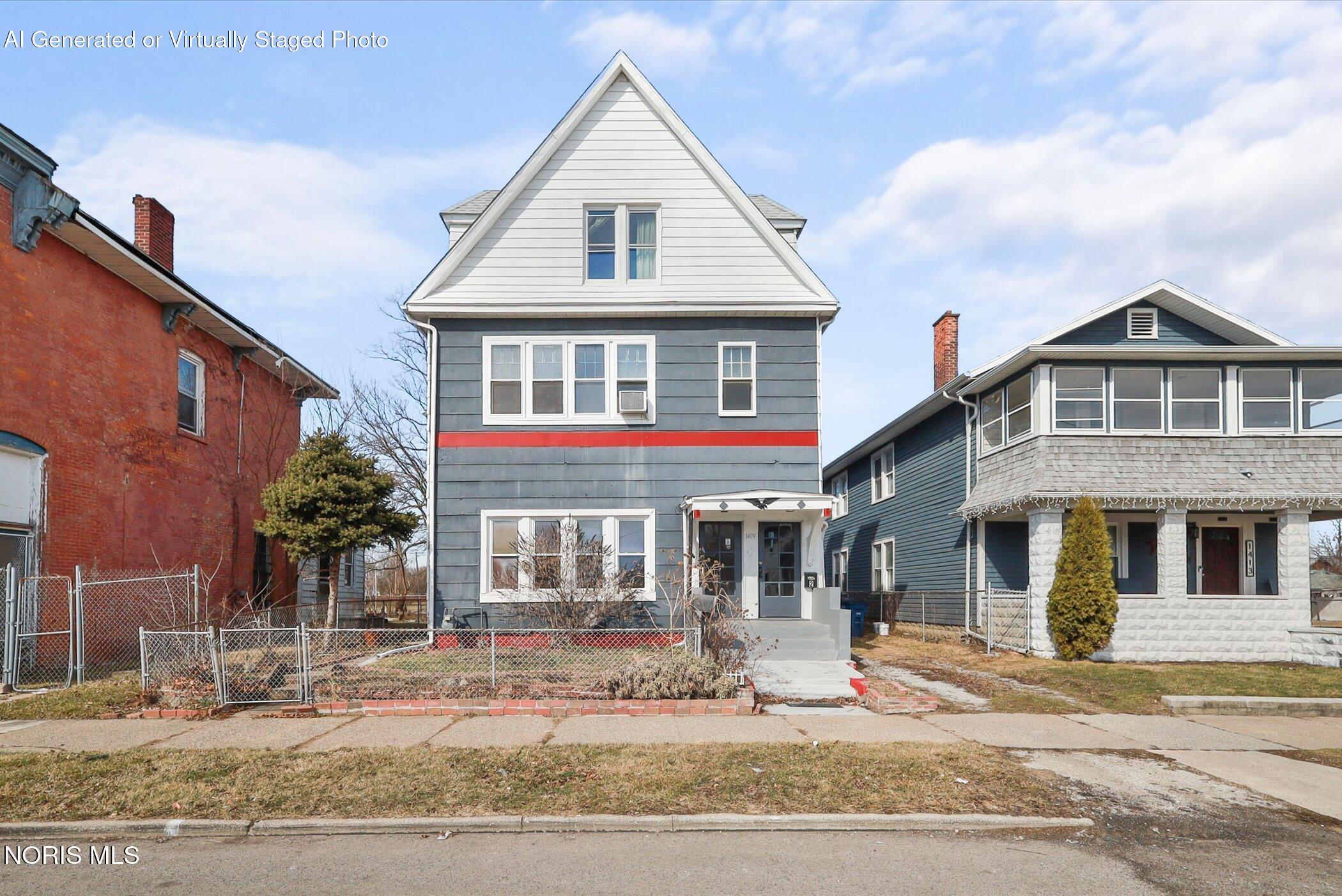 Gray house with a steep white gable, red trim, and a fenced front yard.