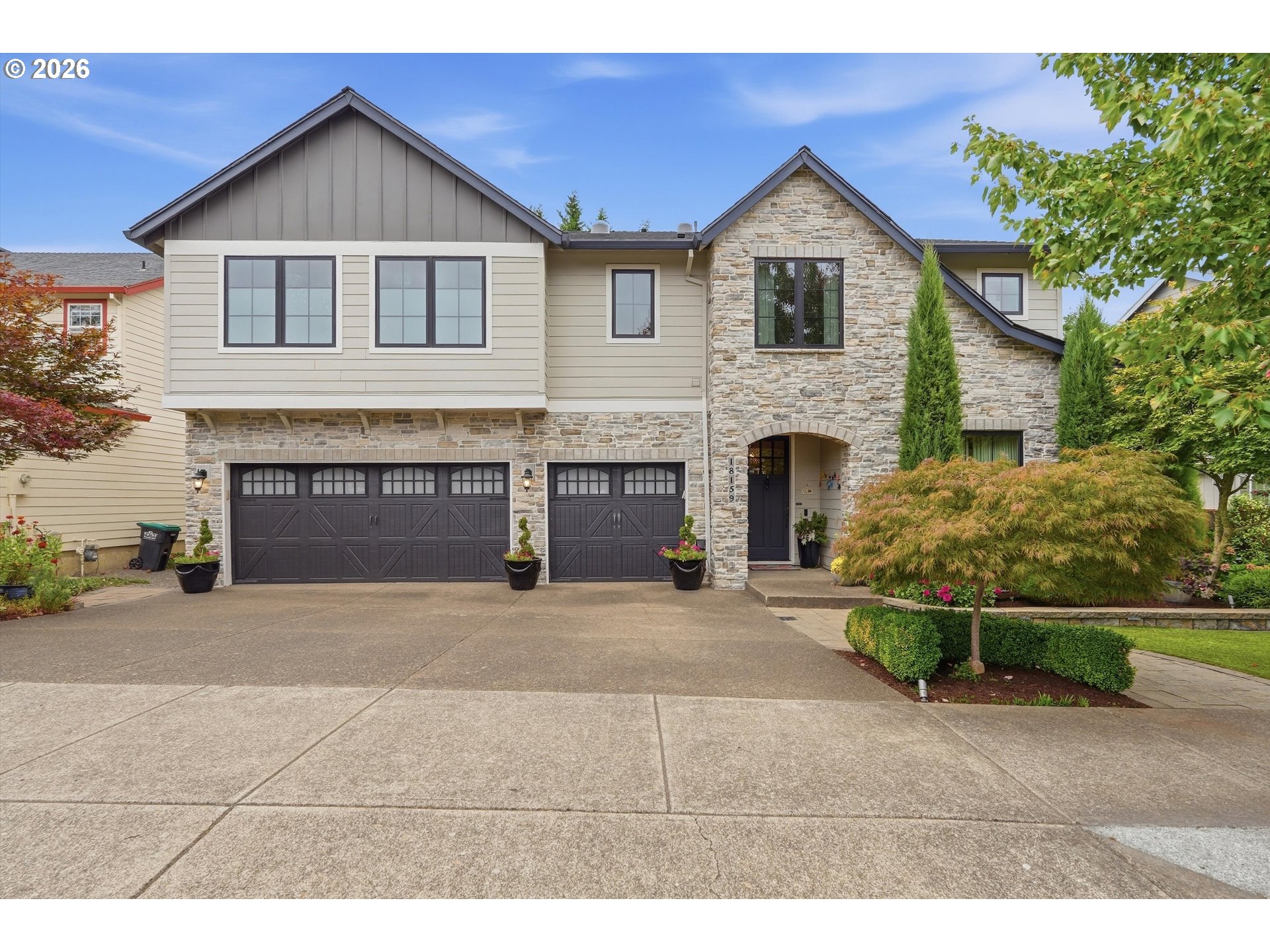 Two-story home with a stone facade, double garage, and landscaped front garden.