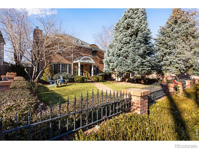 Brick office building behind a wrought-iron fence, with snow-dusted evergreens and a covered entrance.