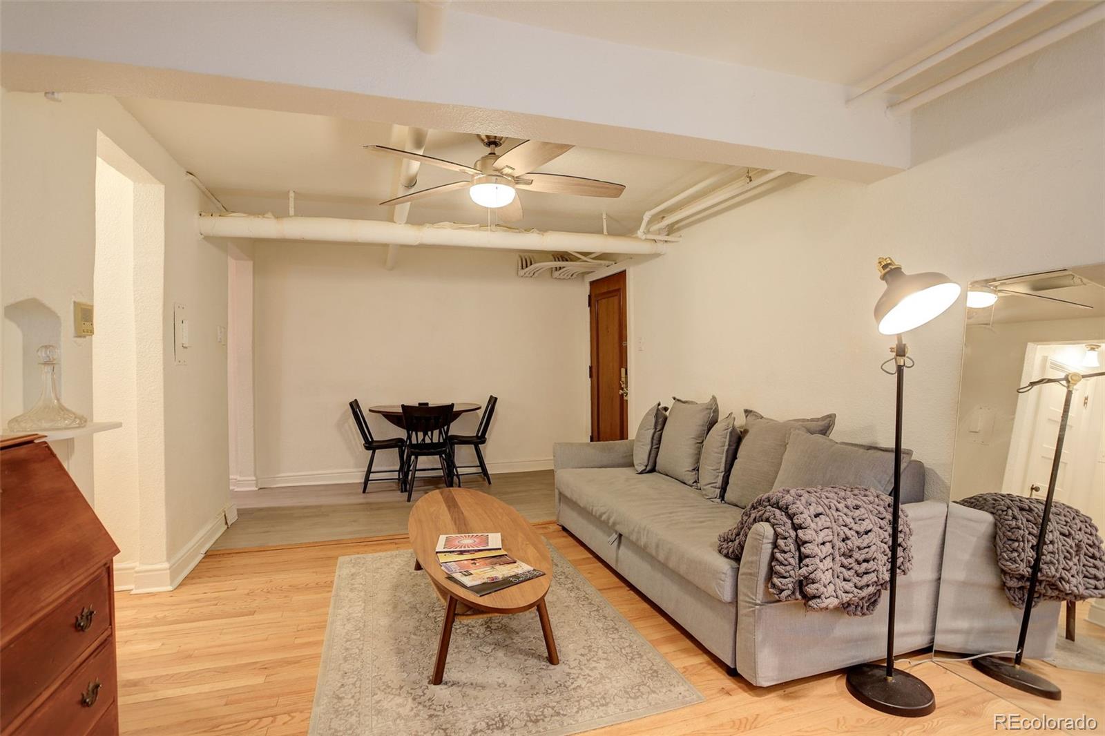 Living room with gray sectional, wood coffee table, patterned rug, and dining area.