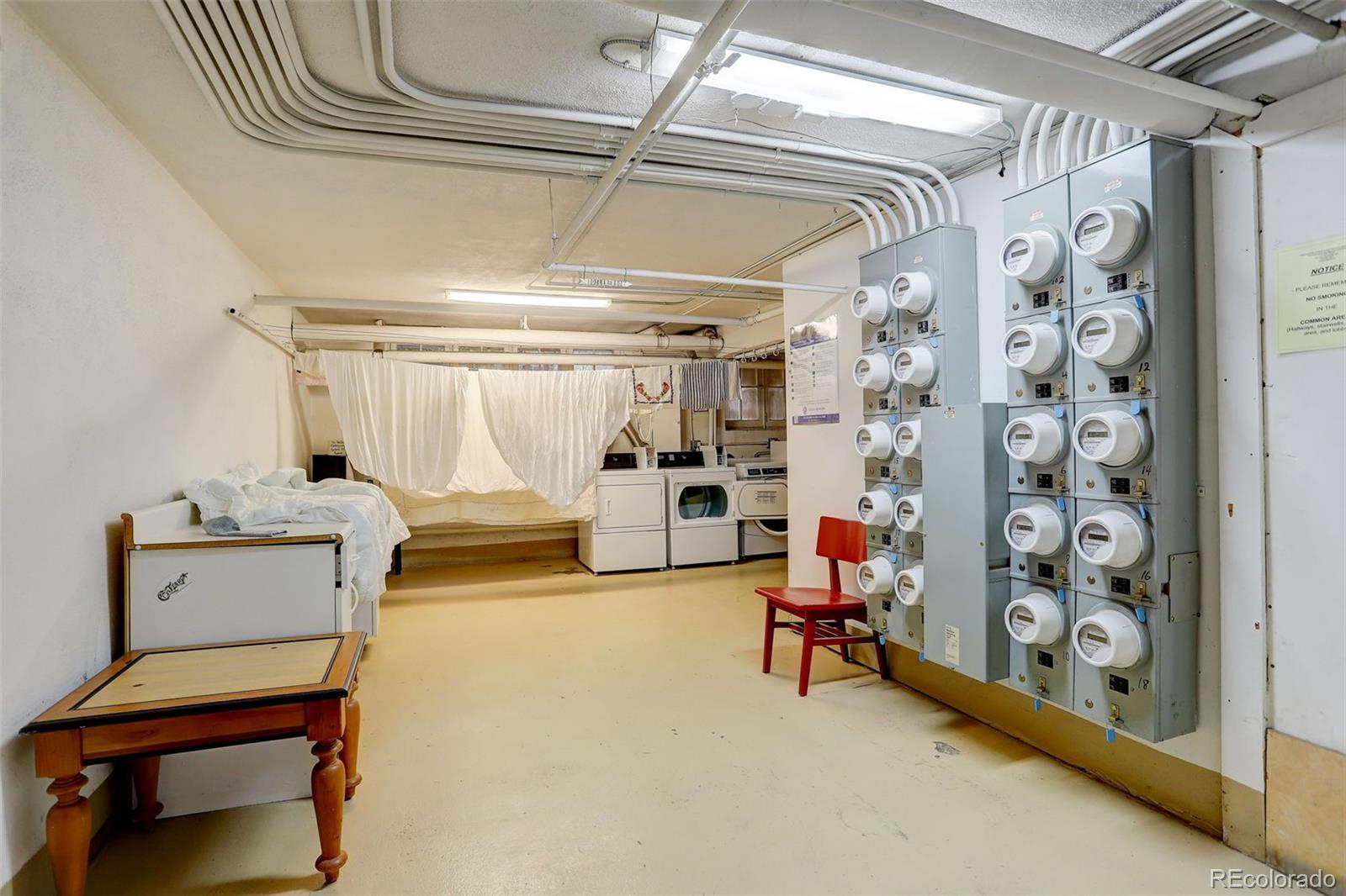 Shared laundry room with washers, dryers, hanging laundry, and utility meters.