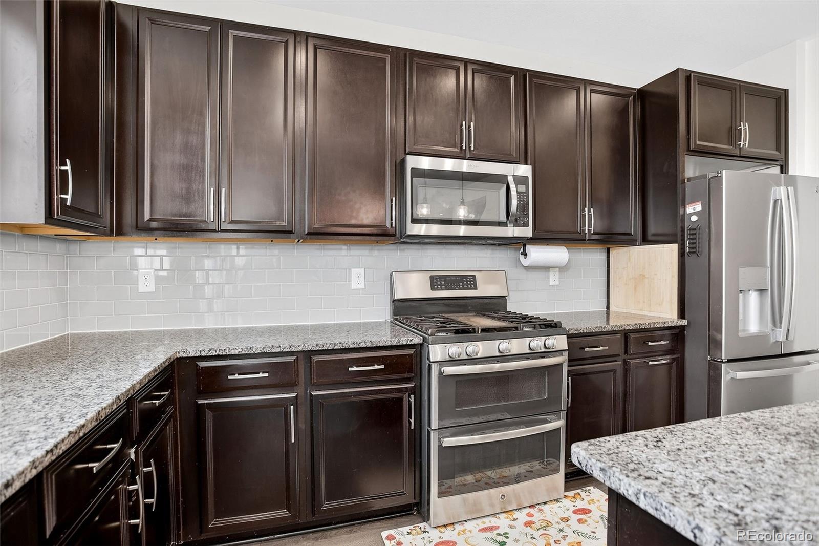 Kitchen with dark wood cabinets, granite counters, and stainless steel appliances.