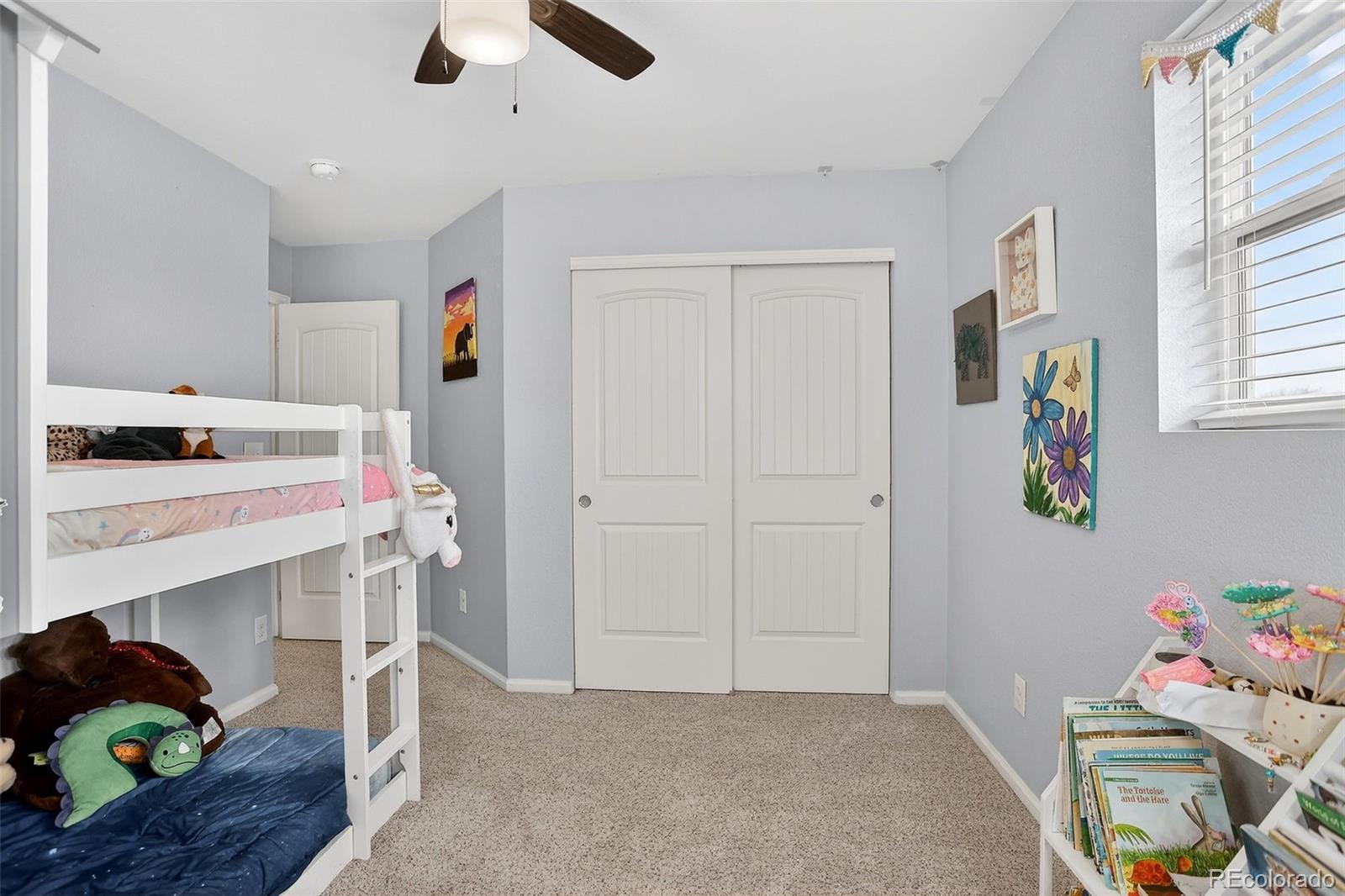 Bedroom with a white bunk bed, sliding closet doors, and colorful children's artwork.