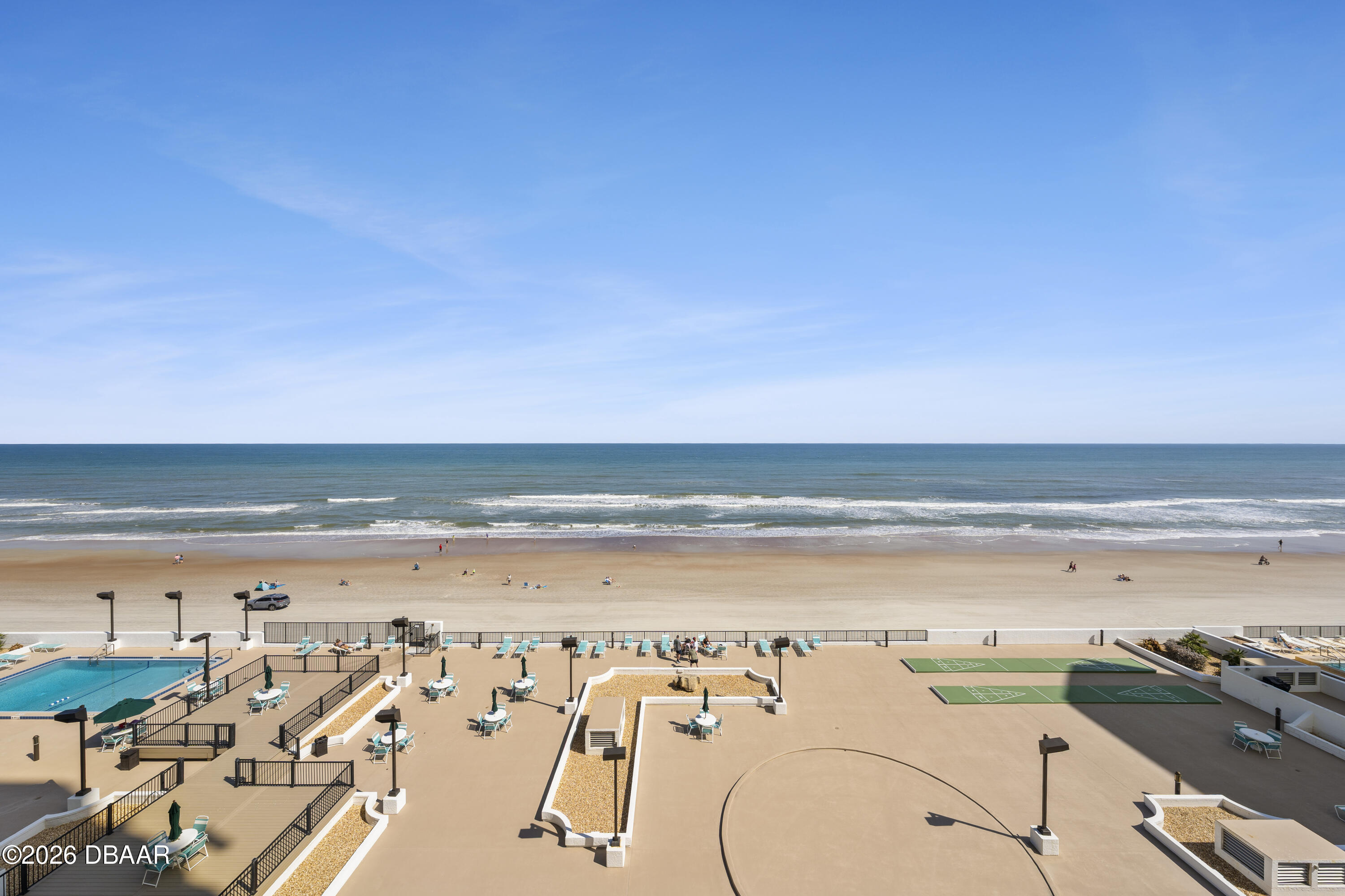 Oceanfront beach and resort deck with a swimming pool and courts.