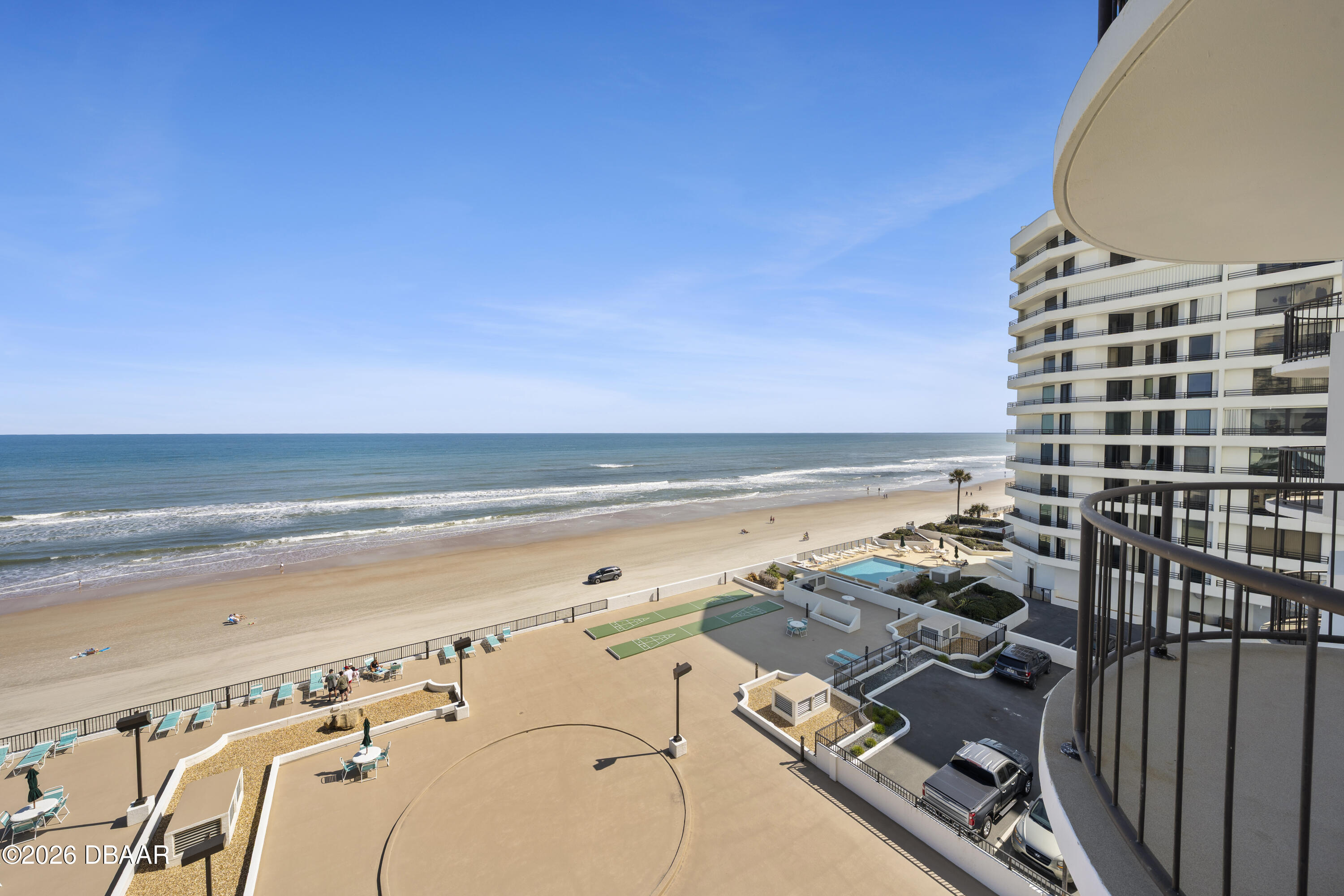Oceanfront condominium and beach viewed from a balcony, with a pool and oceanfront recreation area.
