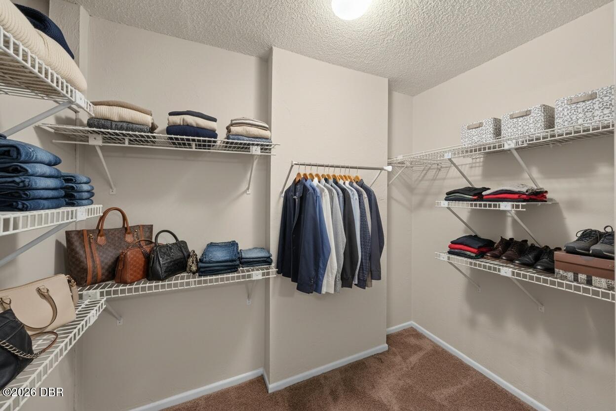Walk-in closet with wire shelving, folded clothes, handbags, and hanging jackets.
