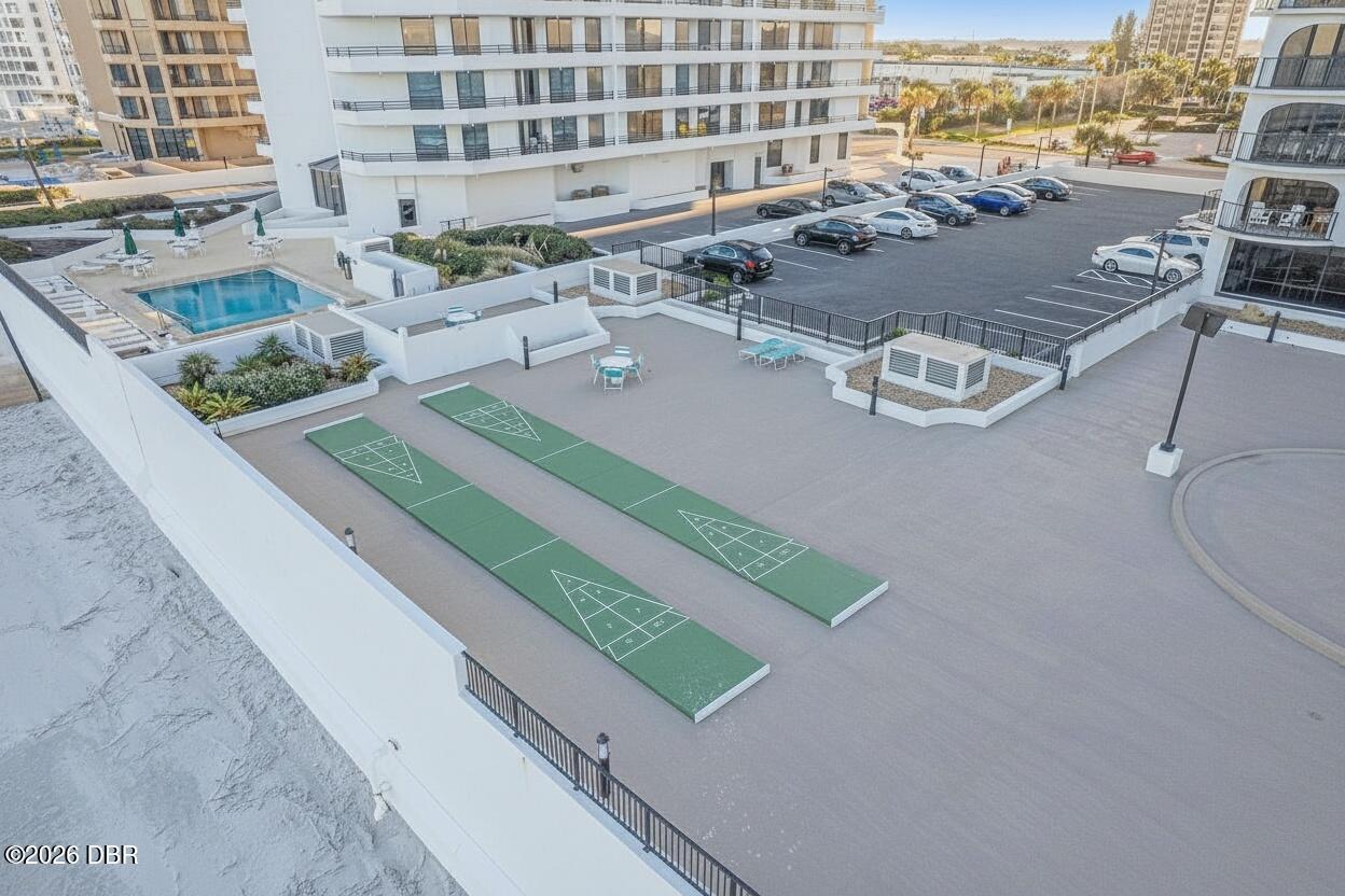 Condominium amenities with shuffleboard courts, a swimming pool, and a parking lot.