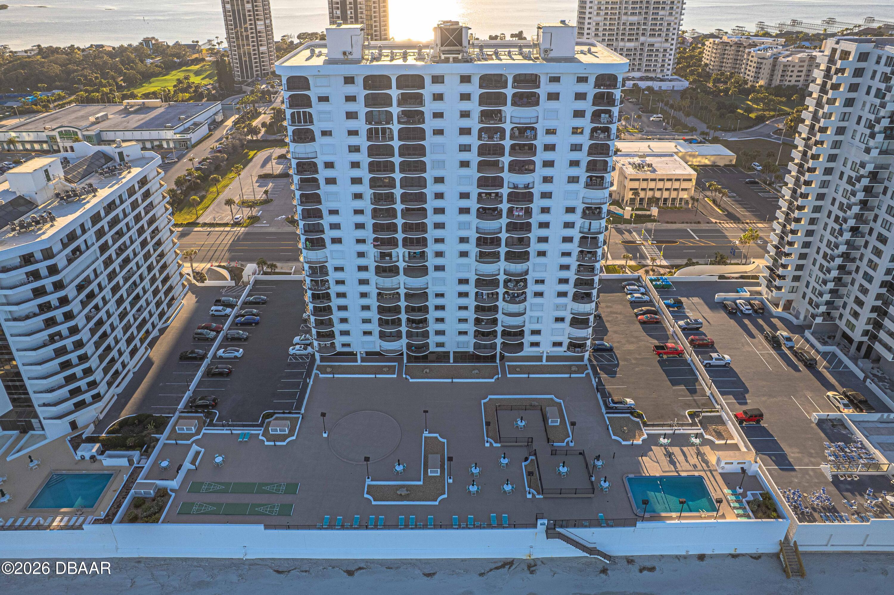 Aerial view of a beachfront condominium with two pools and a broad oceanfront deck.