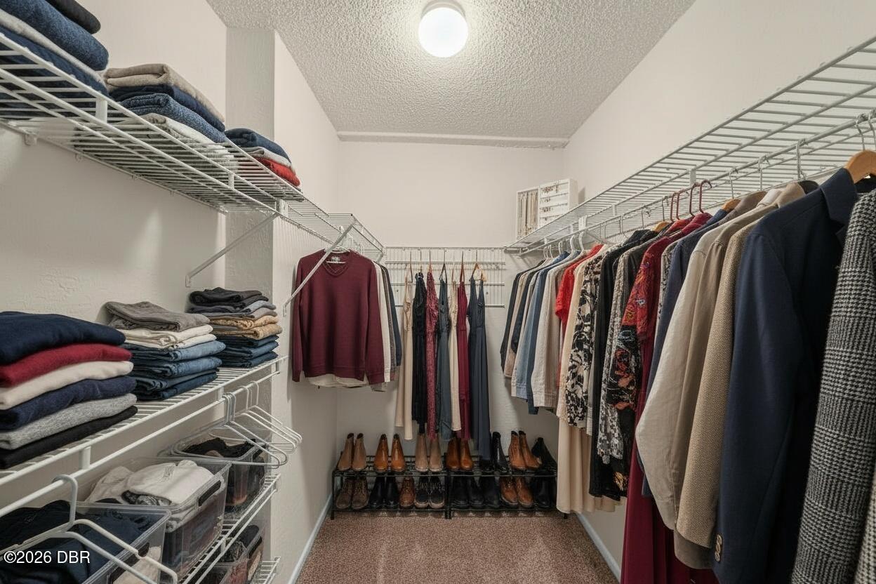 Walk-in closet with wire shelving, neatly folded clothes, hanging garments, and shoes.