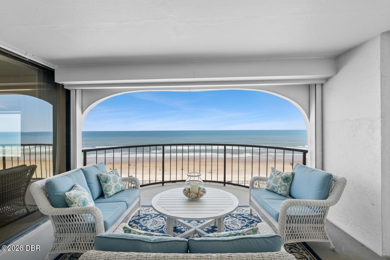 Furnished balcony with blue seating, a patterned rug, and an unobstructed beach view.