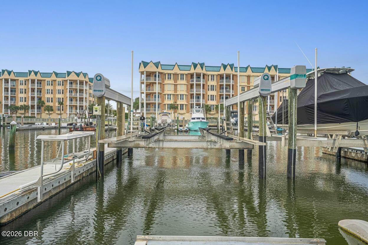 Marina dock with boat slips and condominium buildings across the water.