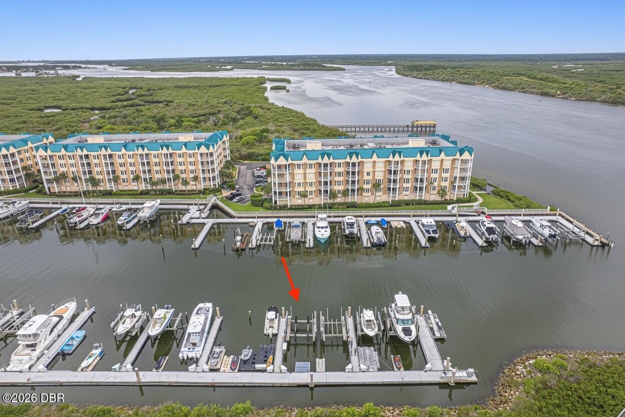 Waterfront condominiums and marina beside a broad river and green marshland.