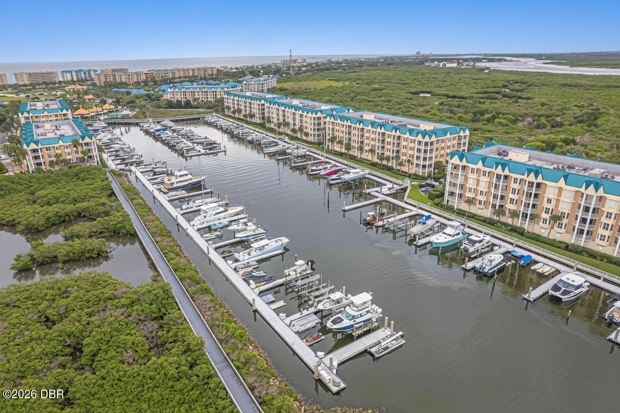 Aerial view of waterfront condominiums and a marina filled with boats, bordered by mangroves.