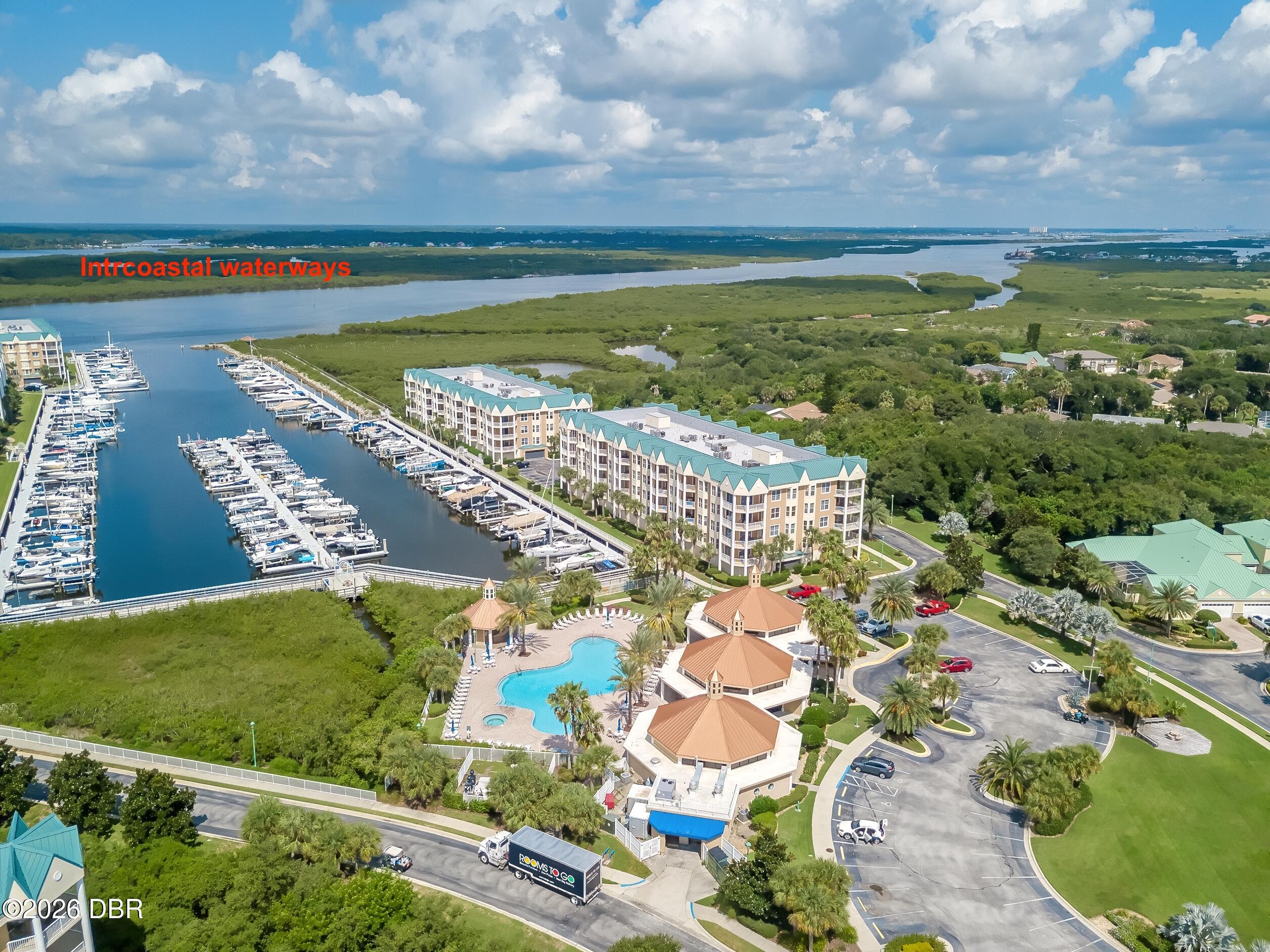 Aerial view of waterfront condominium buildings, marina, pool, and Intracoastal waterways.