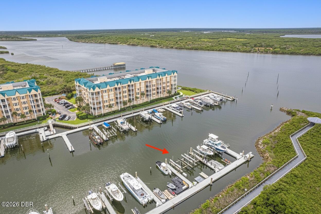 Waterfront condominiums and marina with boats, a red arrow pointing to a dock slip.