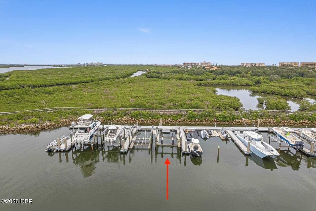Aerial marina with boats, mangrove wetlands, and an arrow marking a slip.