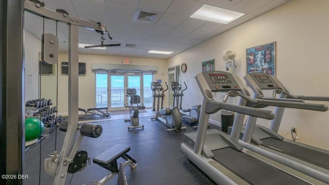 Fitness room with treadmills and exercise bikes beside glass doors overlooking the water.