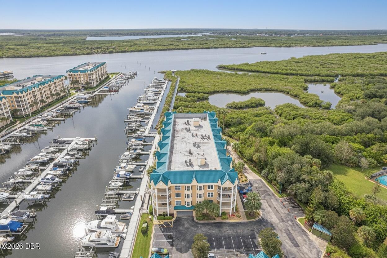 Waterfront condominium beside a marina, with boats, waterways, and surrounding wetlands.