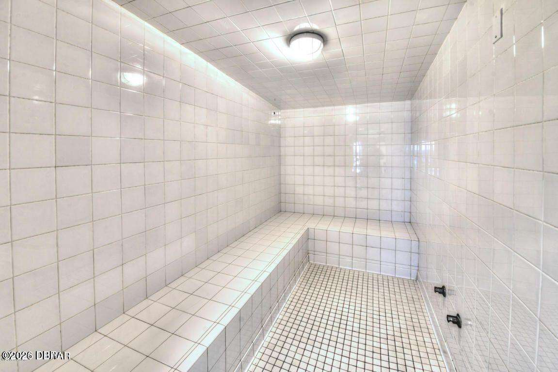 Tiled steam room with a long built-in bench and shower controls.