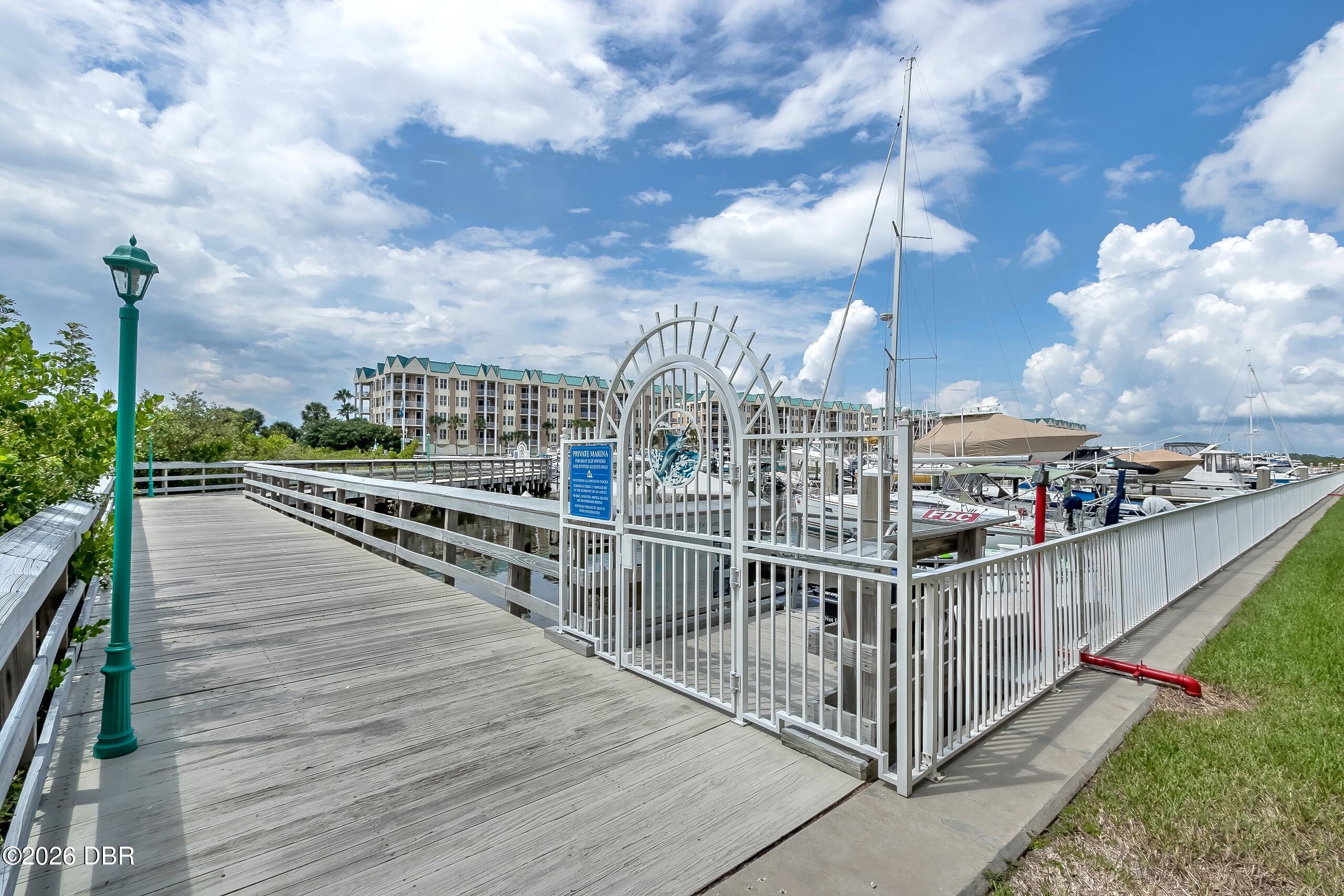 Marina entrance with a gated dock, boats, and a waterfront condominium building.