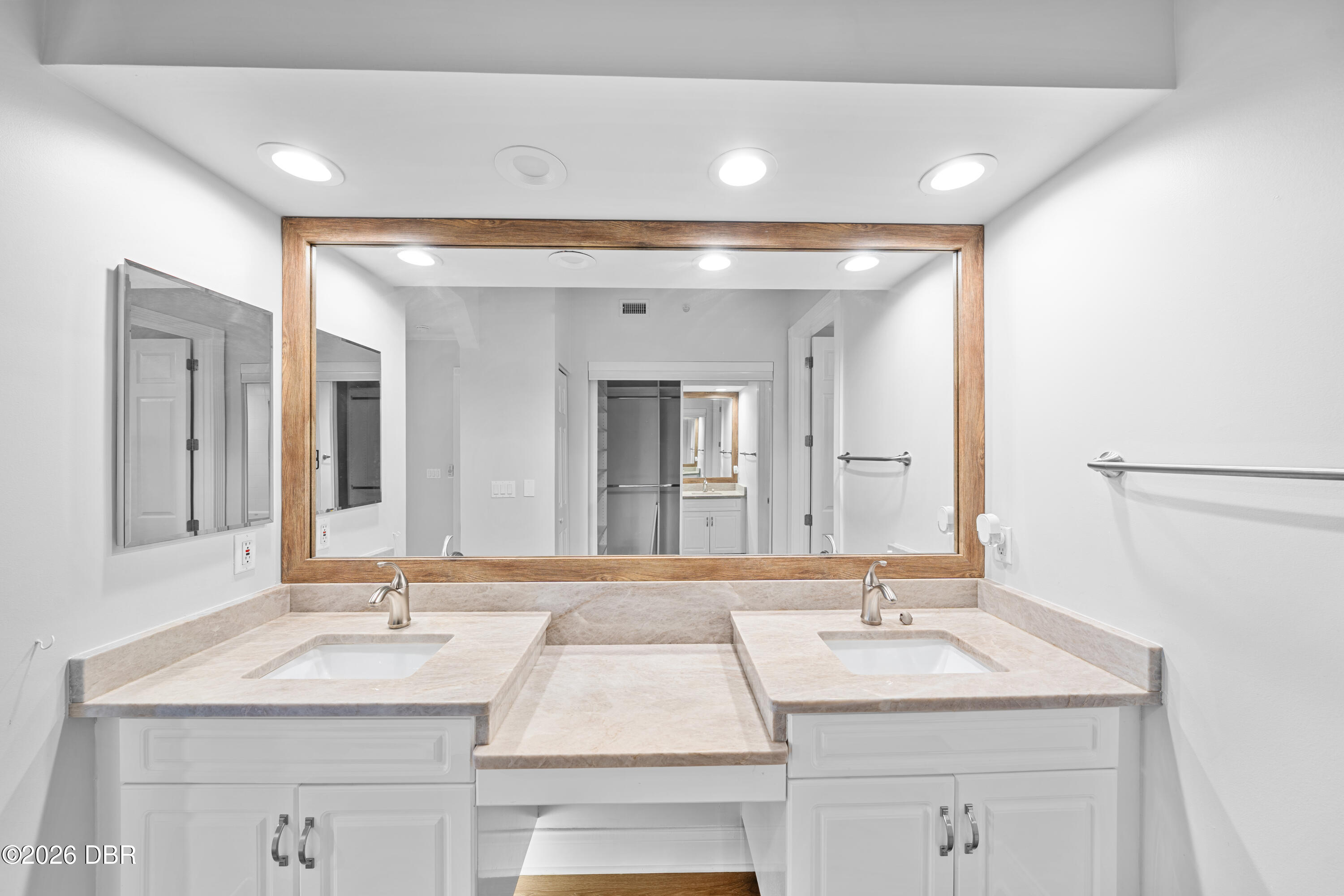 Bathroom vanity with double sinks and a large wood-framed mirror.