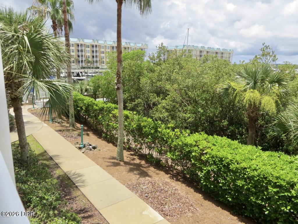 Condominium grounds with a curving walkway, palm trees, and buildings beyond the landscaping.