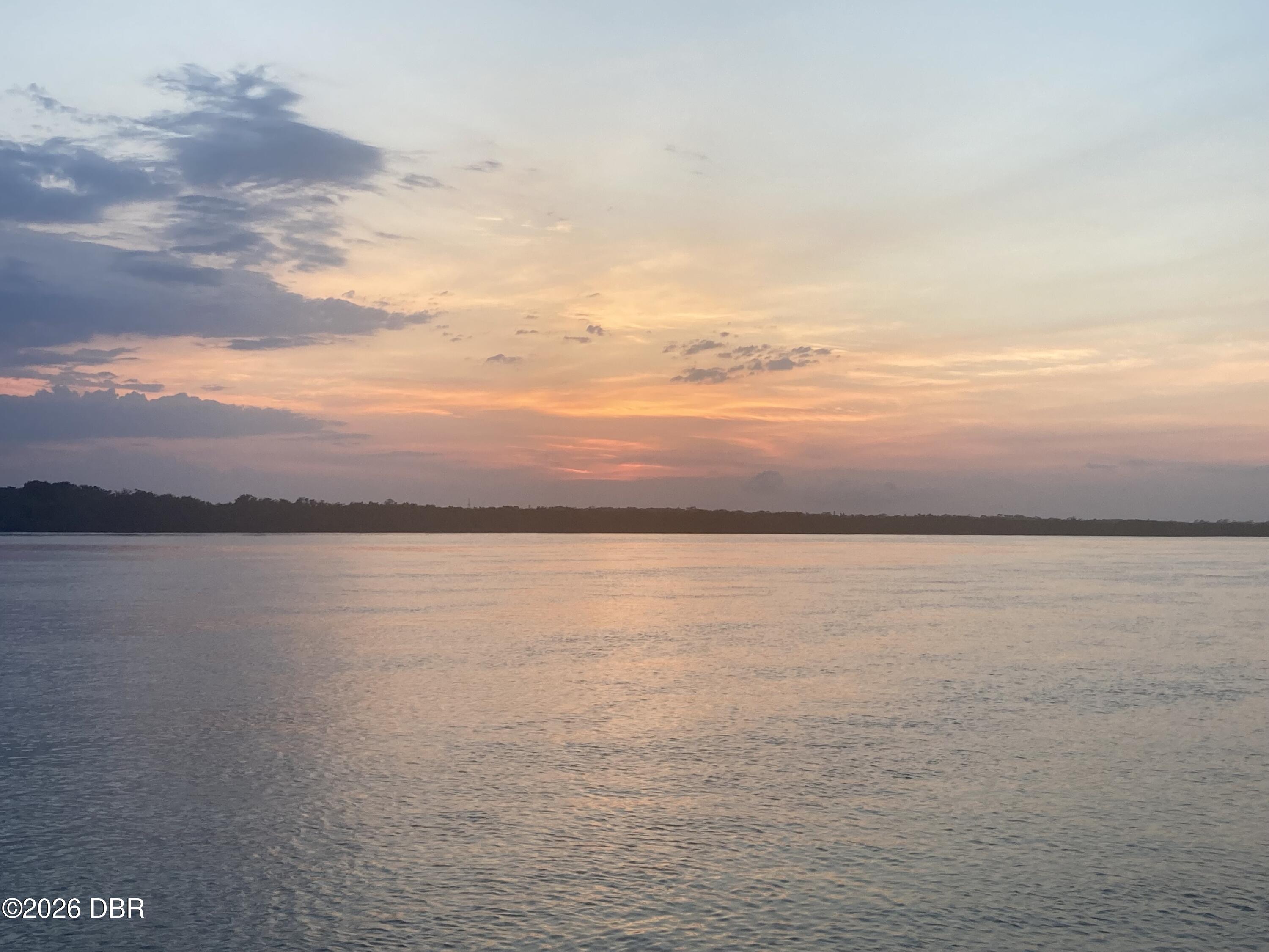 River at sunset with warm reflections and a tree-lined shoreline.