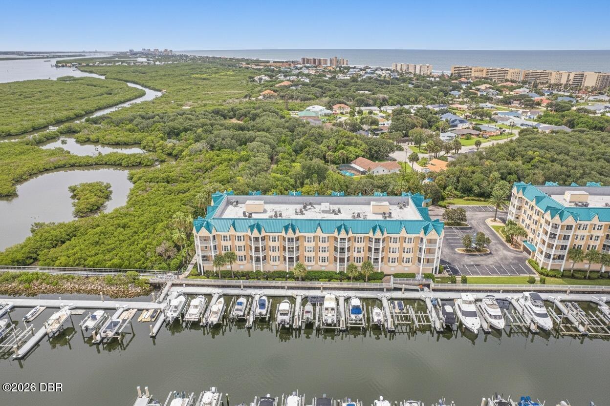 Waterfront condominium and marina beside coastal wetlands, with the Atlantic Ocean in the distance.