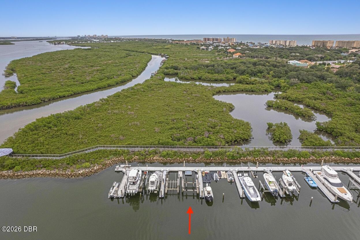 Aerial marina view with boat slips in front of mangrove waterways and the distant ocean.
