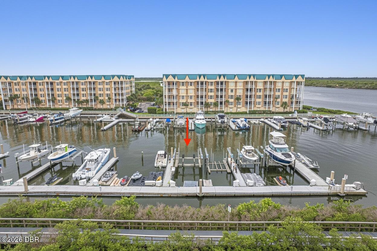 Waterfront condominiums and marina with boats docked in slips; a red arrow marks one slip.