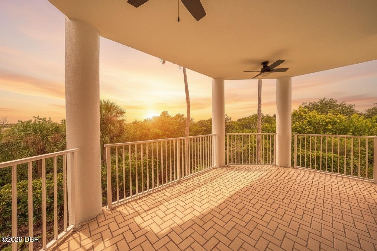 Covered tiled balcony overlooking greenery in warm sunset light.