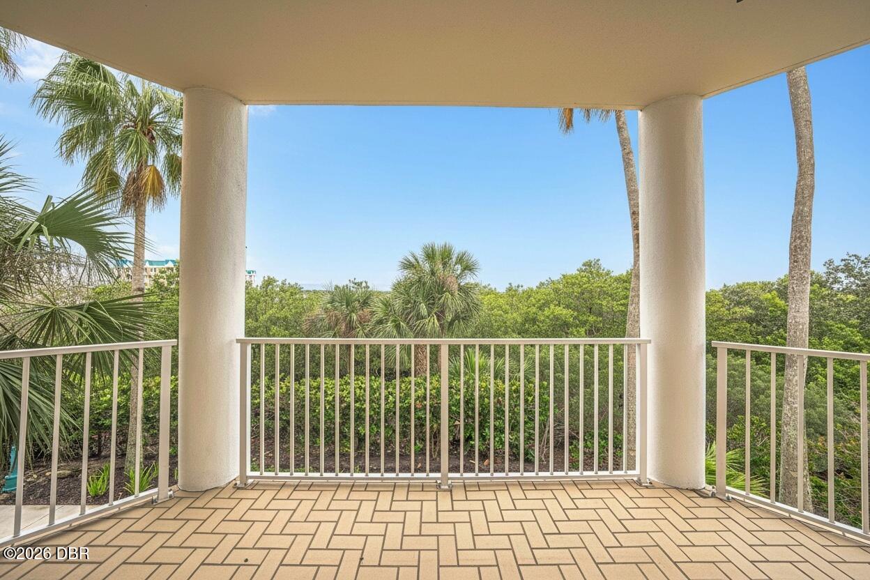 Covered tiled balcony overlooking palm trees and lush greenery.