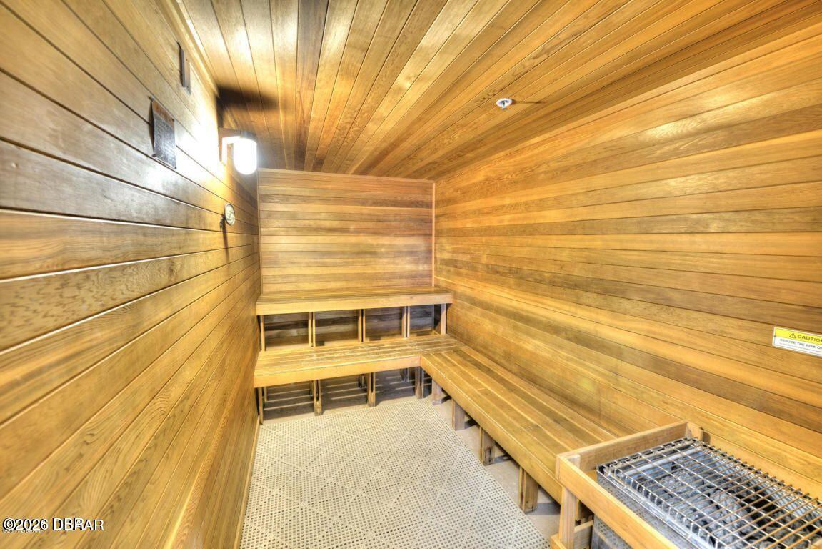Wood-paneled sauna with tiered benches and a metal heater.