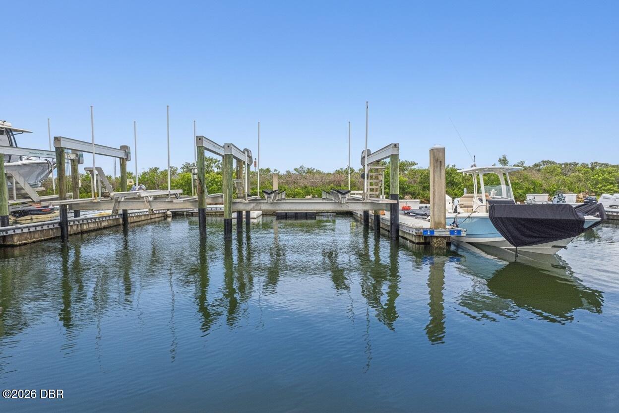 Marina dock with wooden boat slips and boats moored along calm water.