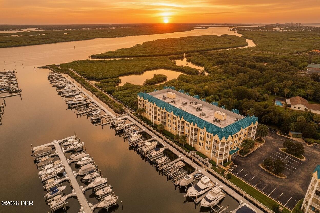 Waterfront condominium and marina with docked boats, mangroves, and a sunset over the water.