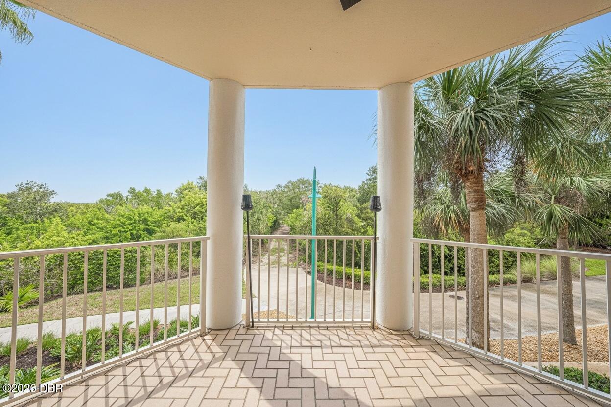 Covered tiled balcony overlooking a tree-lined walkway.