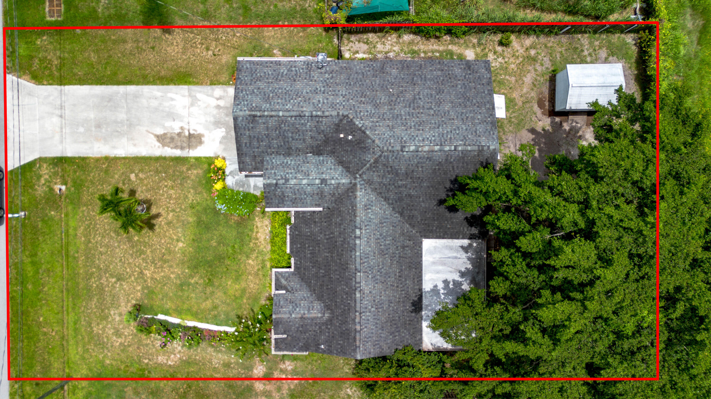 Aerial view of a home and yard, with the property boundary outlined in red.