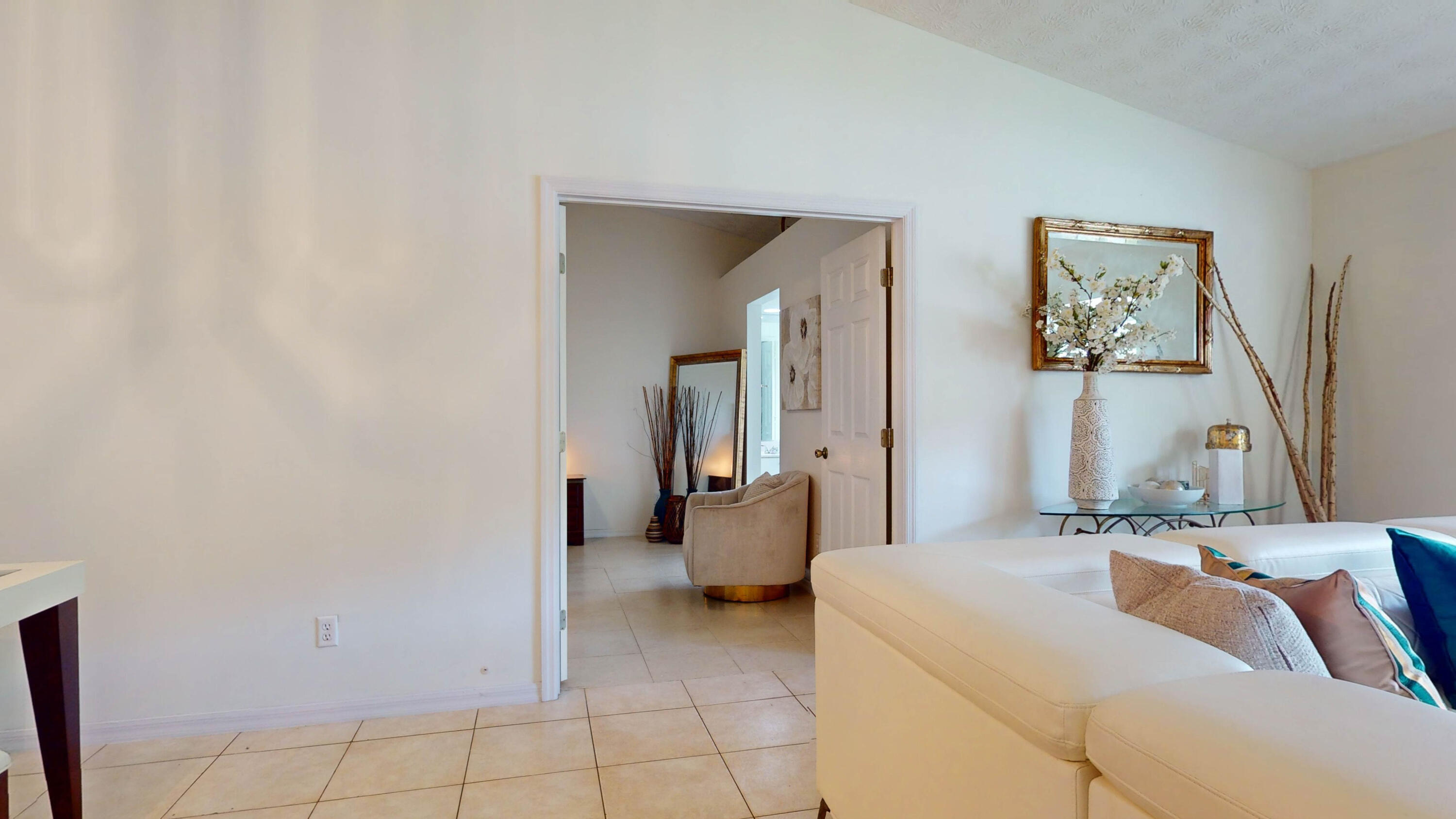 Staged living room with a white sectional sofa and doorway to an adjoining sitting area.