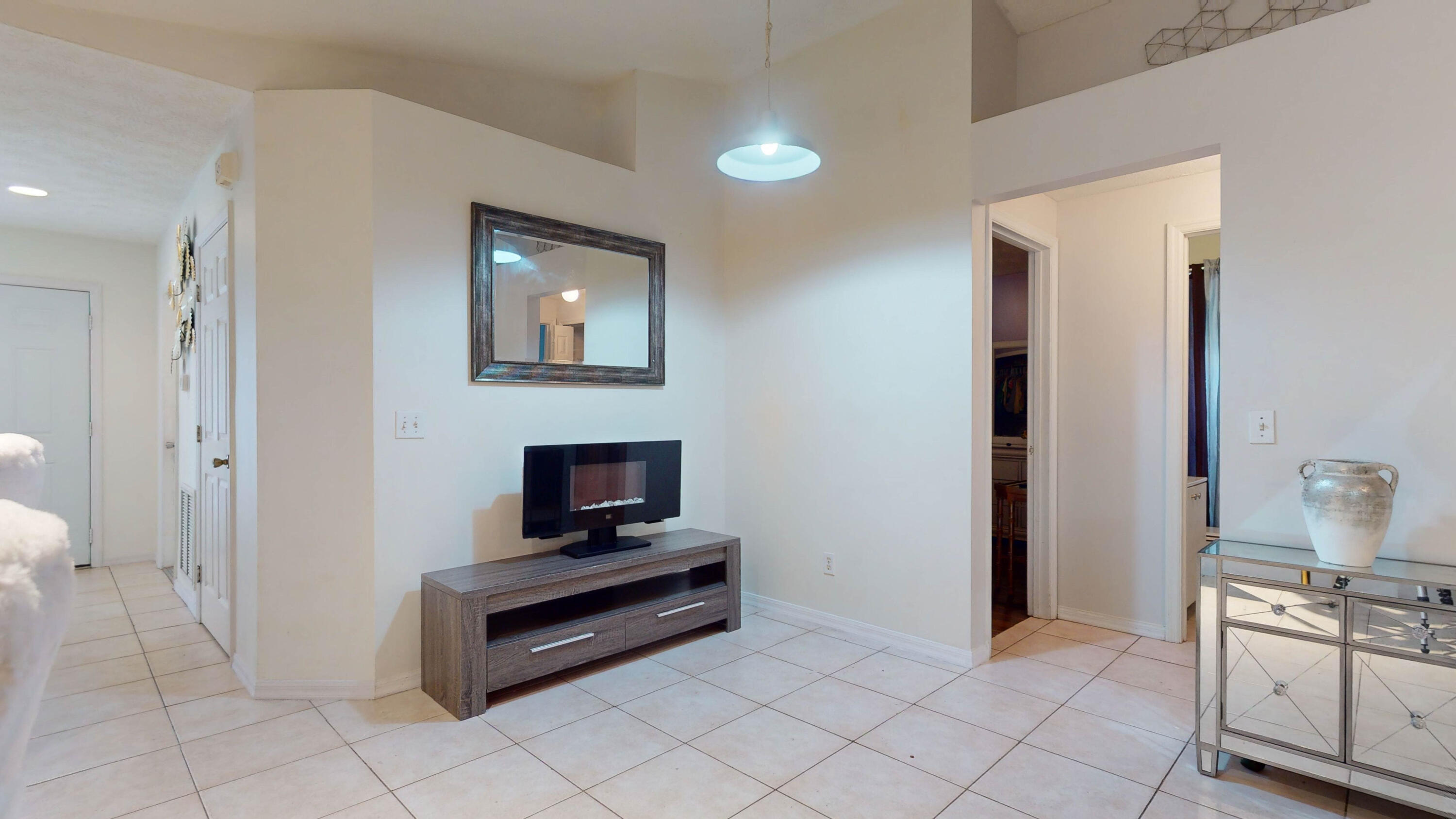 Living area with tiled floors, a wall-mounted electric fireplace, and a wood media console.