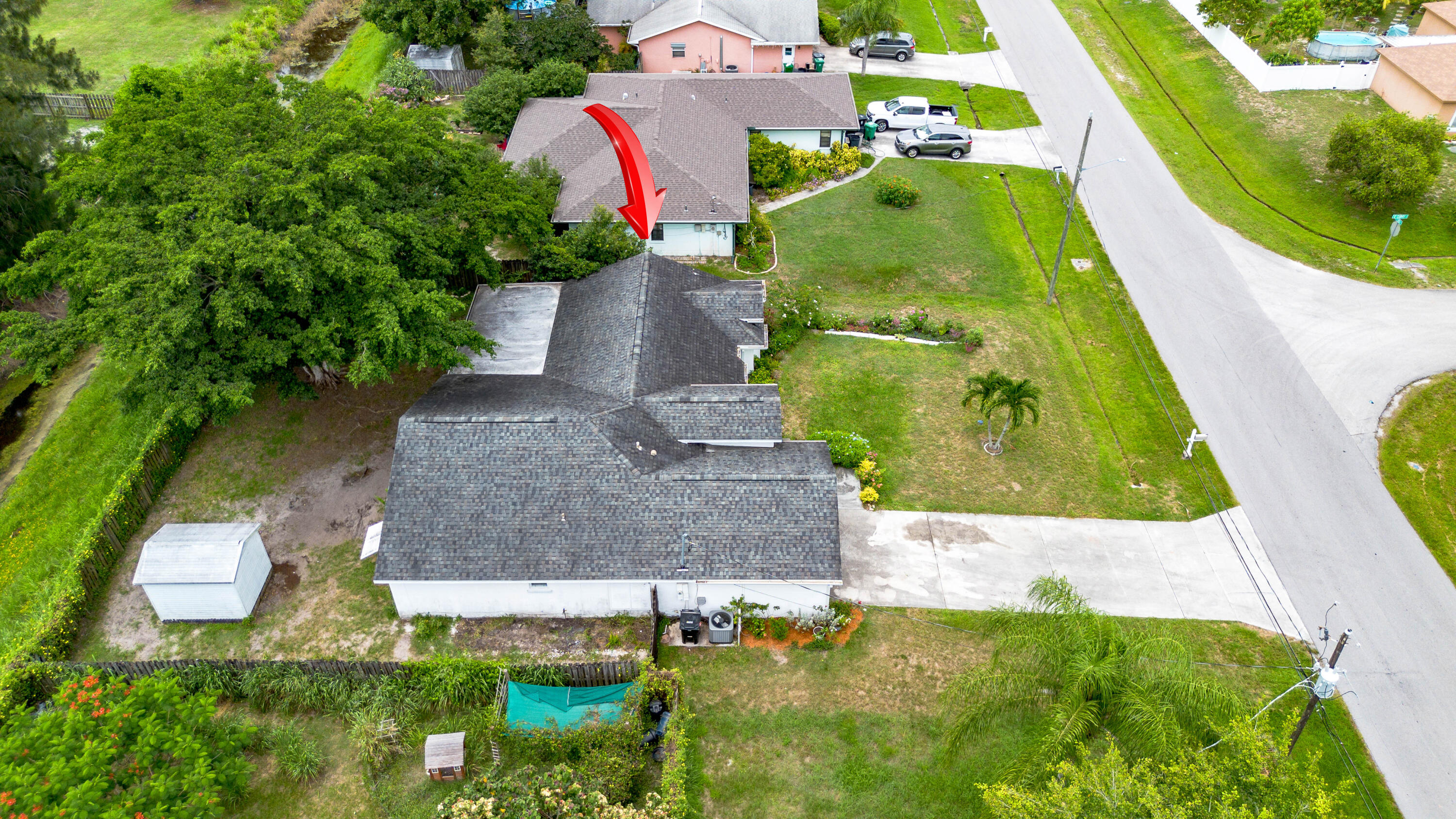 Aerial view of homes and yards, with a red arrow pointing to one house.