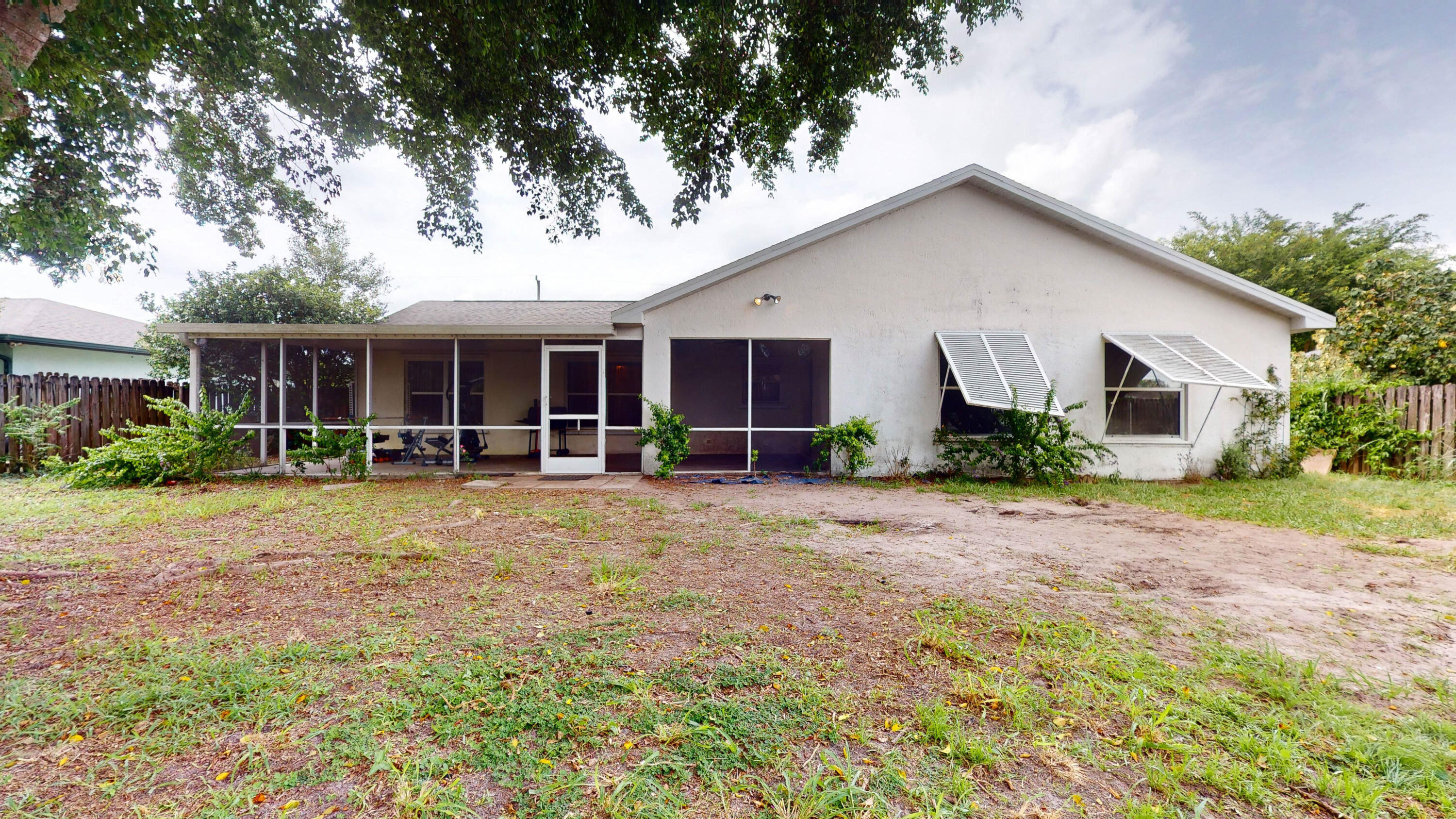 Rear of a single-story home with a screened patio and awning-style window shutters.