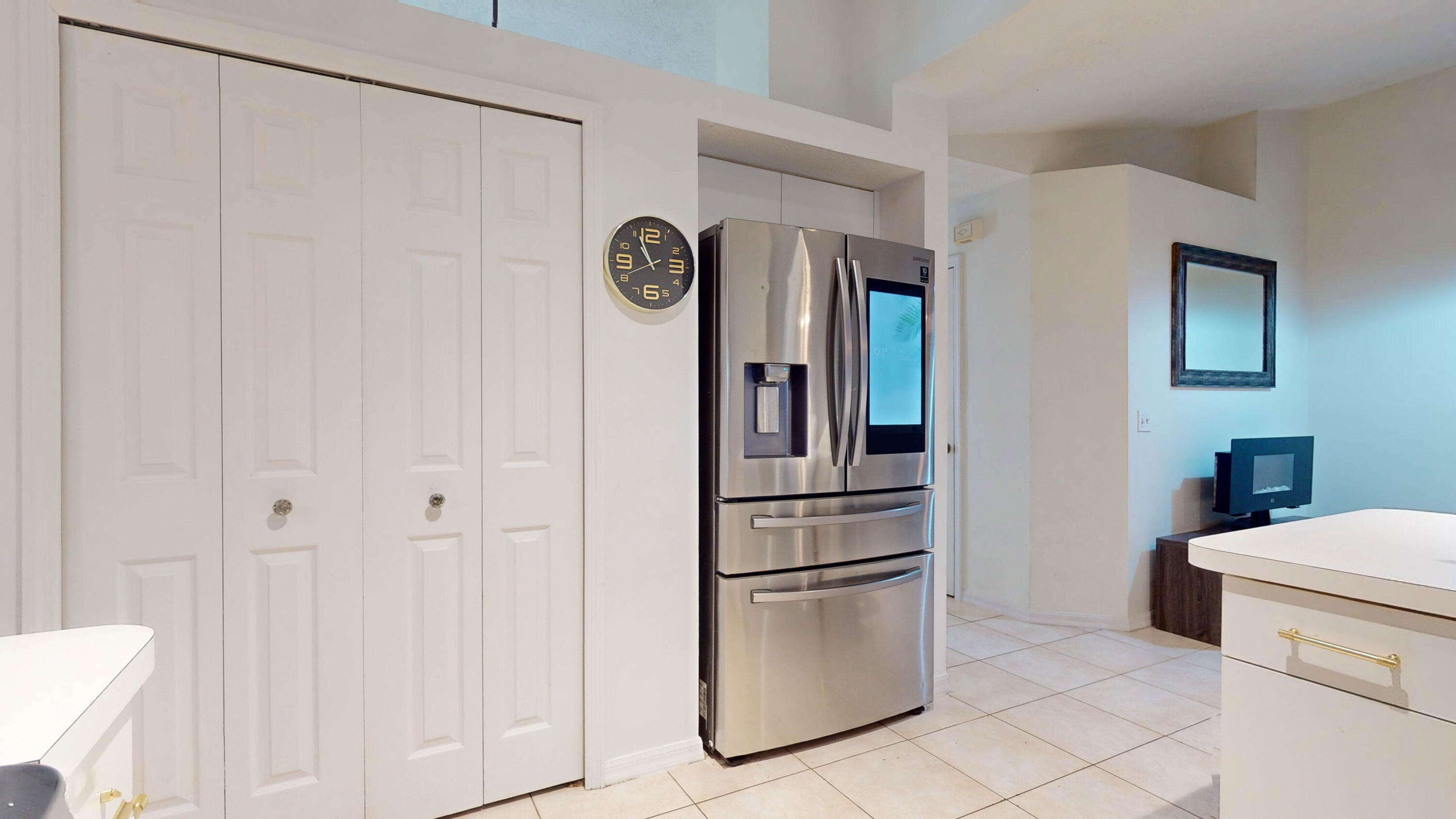 Kitchen with a stainless French-door refrigerator, white cabinetry, and tiled flooring.