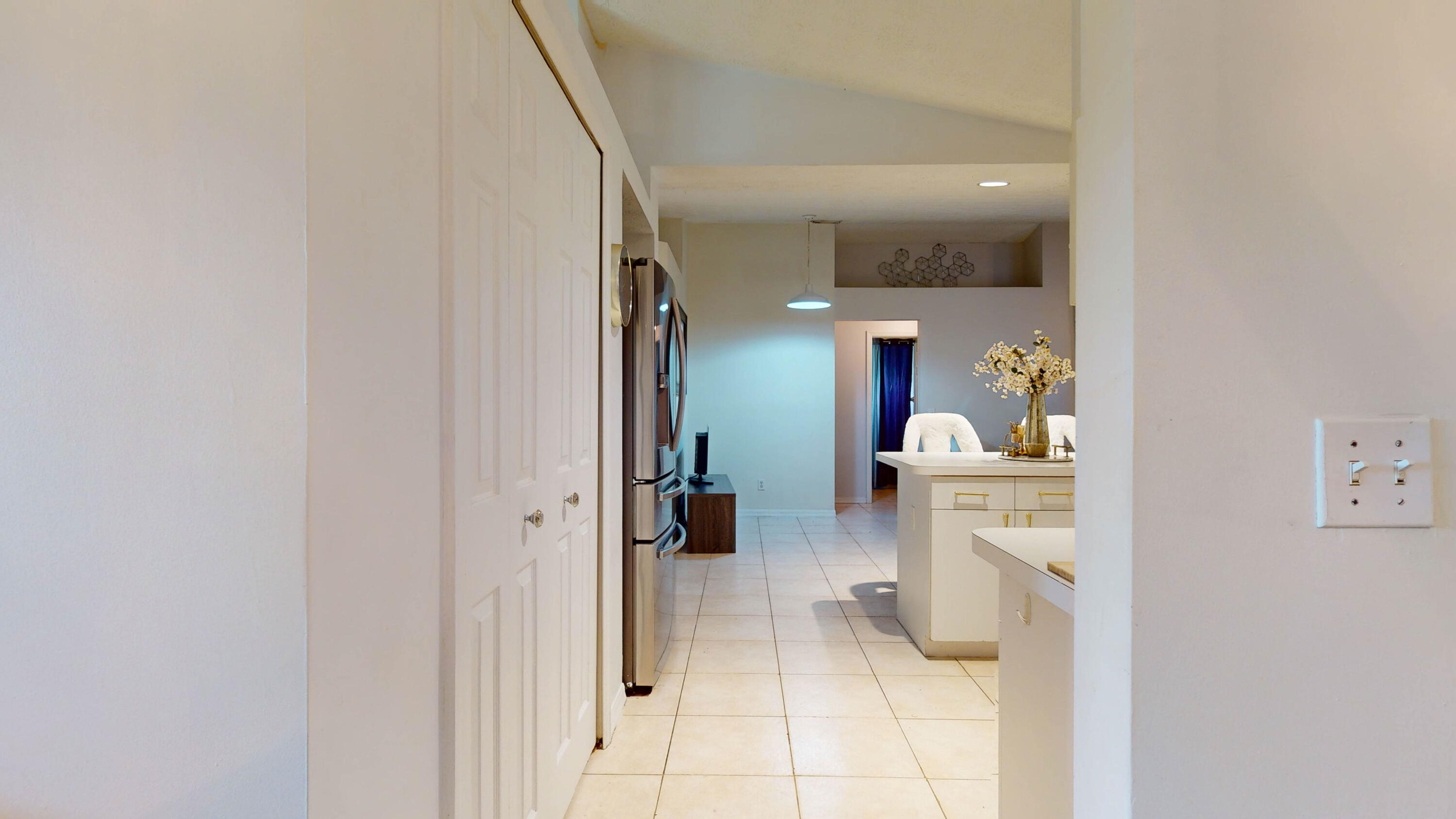 Kitchen with white cabinetry, stainless steel refrigerator, tiled floors, and an adjoining dining area.
