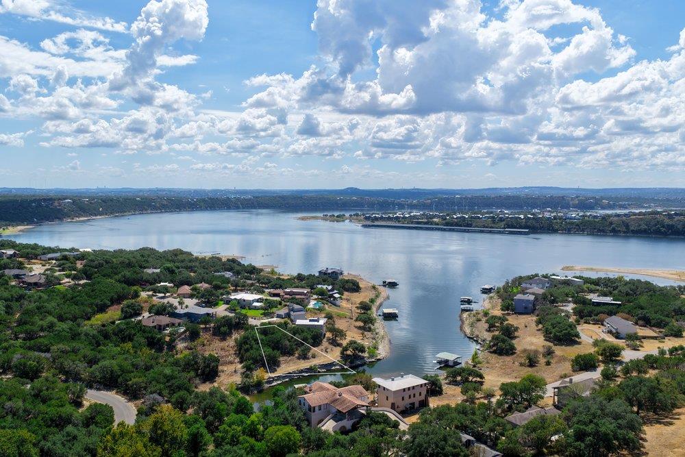 Aerial view of homes along a broad lake beneath a cloud-filled sky.