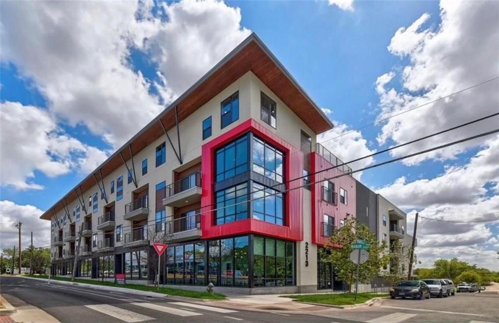 Modern corner apartment building with balconies and a red-framed glass facade.