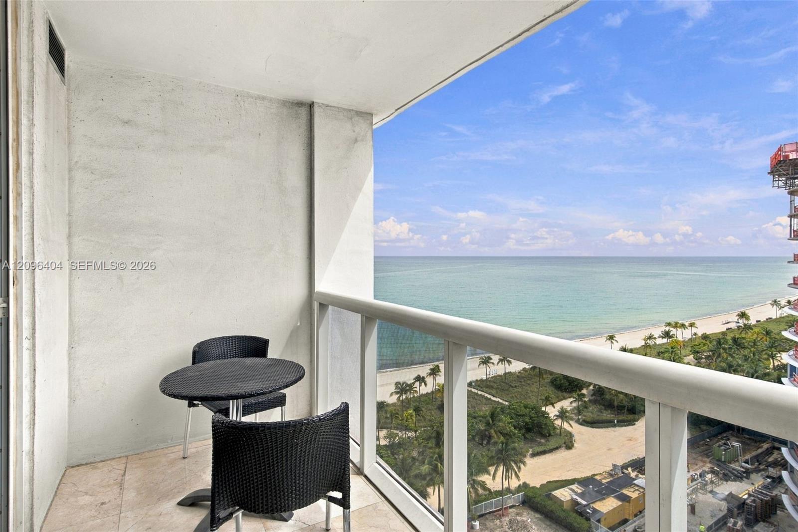 Furnished balcony overlooking the ocean and palm-lined beach.