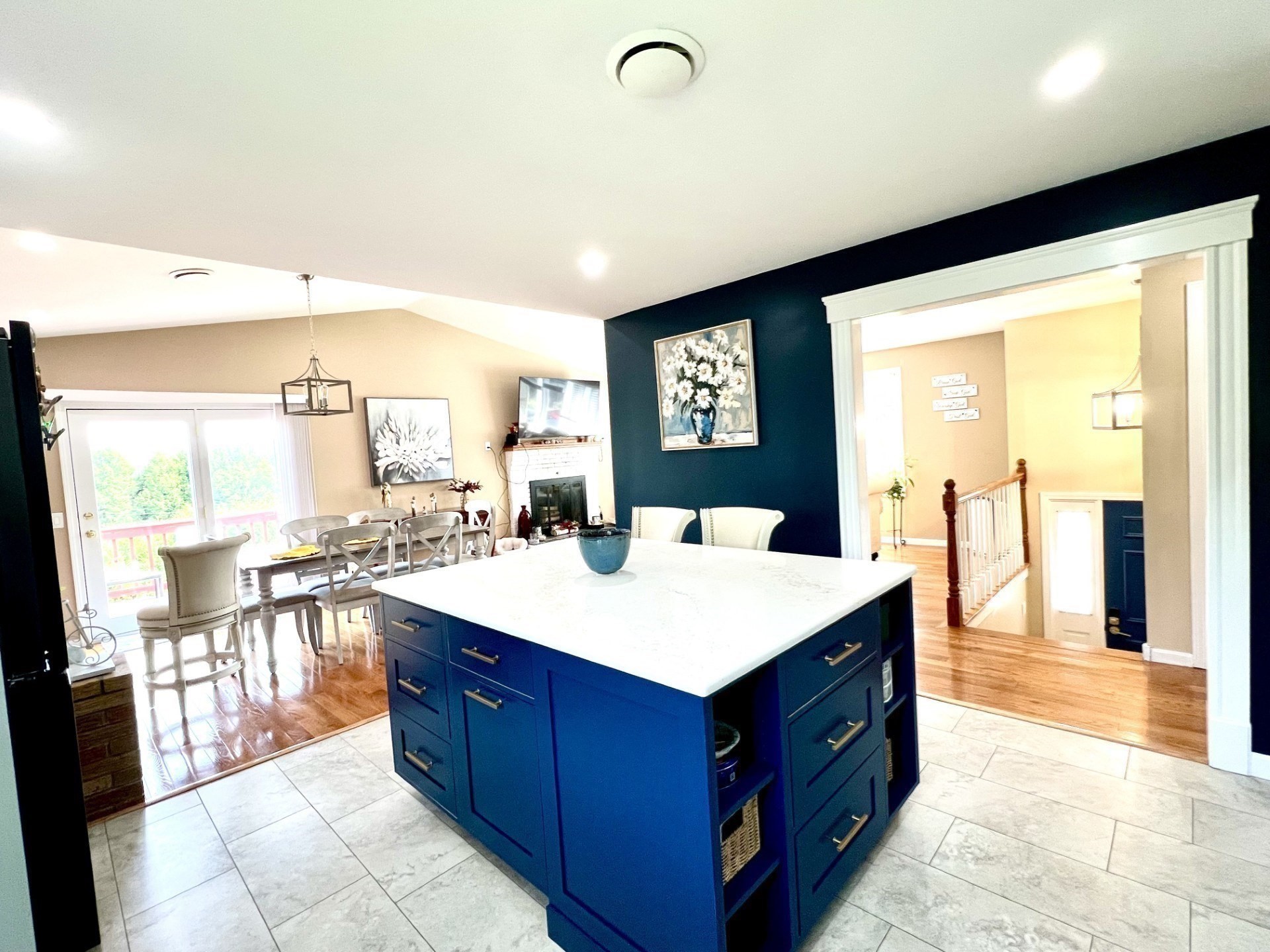 Kitchen with a deep-blue island and white countertop, opening to a dining area.