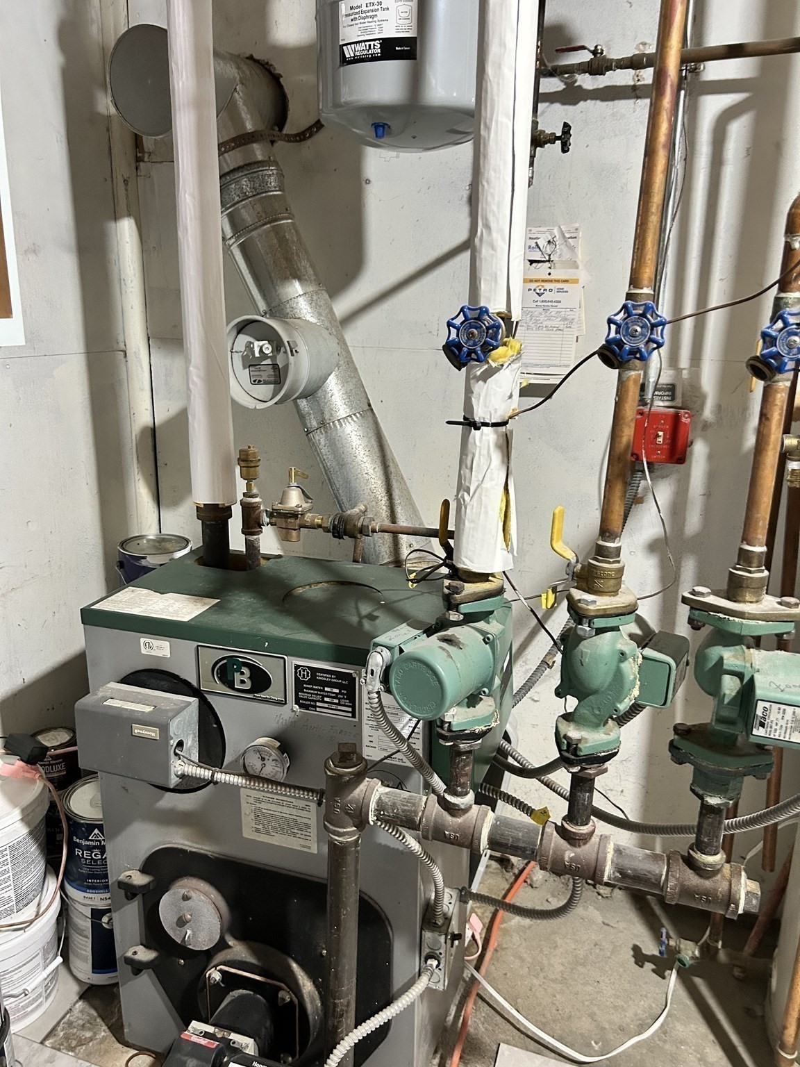 Boiler and exposed piping with blue handwheel valves in the home's mechanical room.